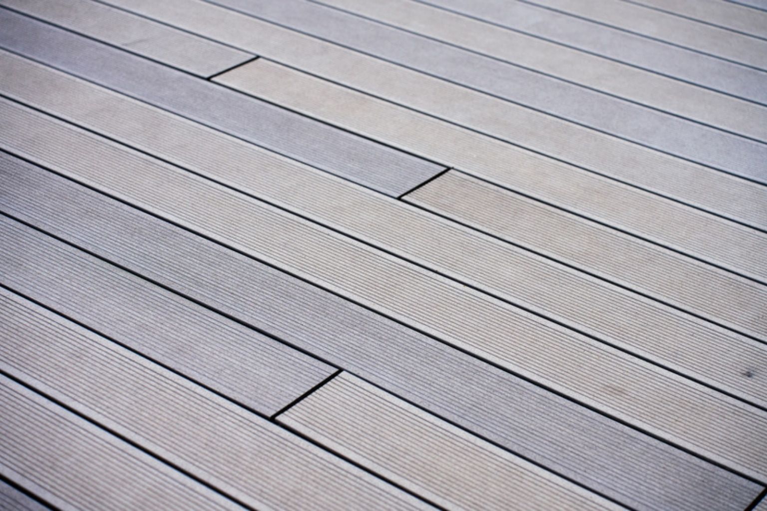 Nærbillede af grå terrassebrædder i komposit lagt i forskudte rækker