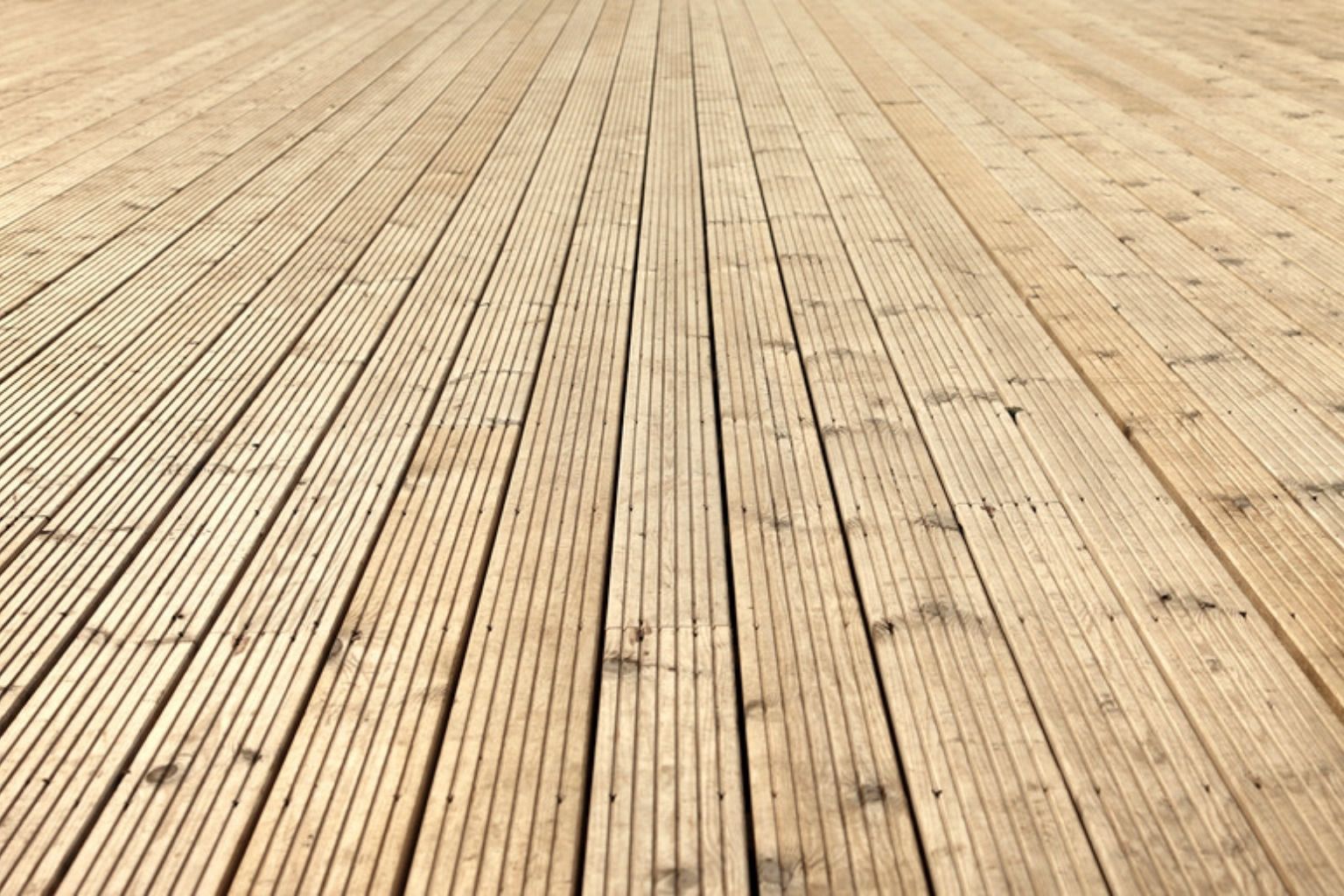 Stor terrasseflade af nye, lyse og rillede terrassebrædder set i perspektiv